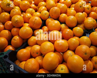 Les oranges sont empilées en grandes quantités sur les étagères d'une épicerie. Les clients parcourent et sélectionnent des fruits frais pour leurs besoins d'achat. Banque D'Images