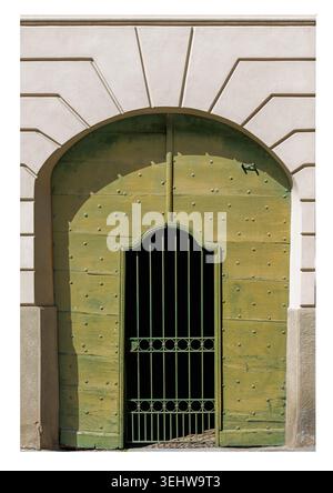Porte arquée en bois vert antique avec clous cloutés en relief, avec porte piétonne intégrée protégée par une grille en fer forgé ; isolé sur un blanc Banque D'Images