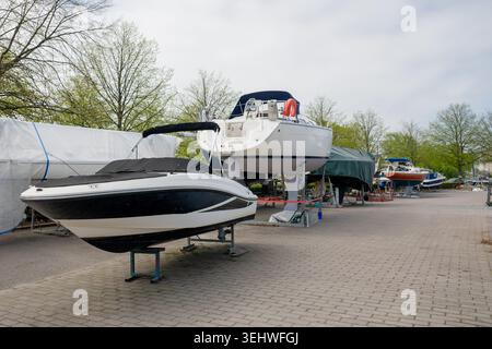 Bateaux stockés sur cale sèche dans la cour de service de la marina avec yachts couverts et zone de maintenance Banque D'Images