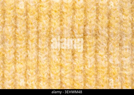 Motif en tissu tricoté en laine jaune pâle. Macro texture d'un pull montrant des détails de fil tissé. Maille en cachemire doux avec motif géométrique détaillé Banque D'Images