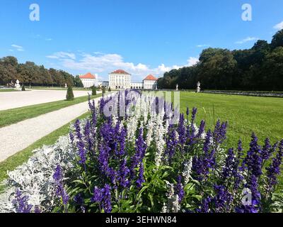 Une belle vue panoramique avec des fleurs violettes et blanches en fleurs au premier plan, avec l'architecture élégante du palais visible en arrière-plan Banque D'Images