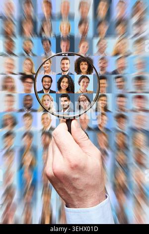 Une main tenant une loupe sélectionne le candidat idéal parmi une foule de professionnels des affaires, un concept de ressources humaines. Banque D'Images