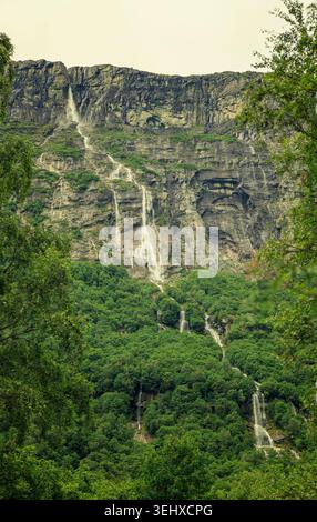 Skorga, Norvège - 22.05.2026 : une falaise accidentée avec plusieurs fines chutes d'eau blanches et une mousse verte luxuriante. Banque D'Images