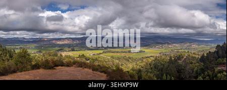Un large paysage panoramique cheminant le long d'une limite rustique de barrière de rail fendu surplombant une vaste vallée de montagne verte Banque D'Images