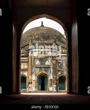 Une vue à travers une porte voûtée révélant un Cheikh Mahmud Shah Masjid historique, bâtiment surmonté d'un dôme avec des détails complexes en pierre - 01 septembre 2025 Banque D'Images