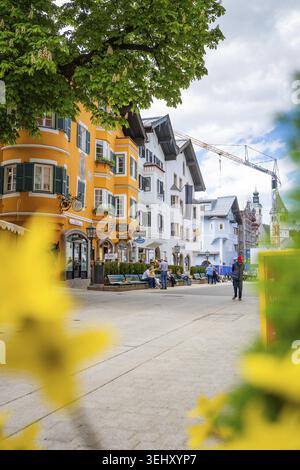 Scène de rue colorée au printemps avec bâtiment jaune, fleurs de construction et grue de construction en arrière-plan, Kitzbuehel, Autriche, Allemagne Banque D'Images