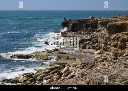 Pêcheur debout sur des falaises rocheuses au-dessus de la mer le long de la côte jurassique sur l'île de Portland dans le Dorset, Angleterre Banque D'Images