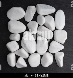 Galet de marbre blanc, pierre de jardin décorative sur noir. Roche de rivière lisse, gravier zen rond, galet de calcaire blanc naturel pour spa et décoration Banque D'Images