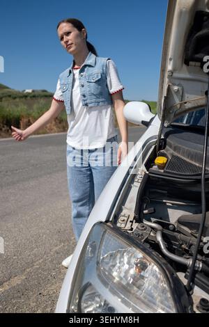 Femme en auto-stop pour l'aide avec la voiture en panne Banque D'Images