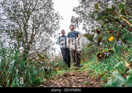 Deux hommes marchant sur un sentier forestier vert Banque D'Images