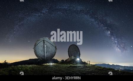 Vue sur les grandes antennes paraboliques du Monte Giogo sous l'arc de la voie lactée et un ciel étoilé en Toscane, Italie. Banque D'Images