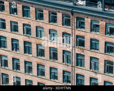 Gros plan photographie aérienne par drone d'une façade moderne d'immeuble d'appartements en brique à Leeds West Yorkshire UK montrant des motifs géométriques de fenêtres et une re urbaine Banque D'Images