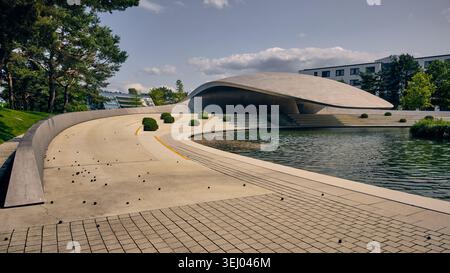Wolfsburg, Allemagne - 06 juin 2025 : vue du Pavillon Porsche d'Autostadt avec son toit incurvé emblématique, l'eau environnante et un paysage moderne Banque D'Images