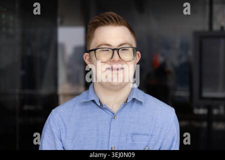 Portrait d'homme professionnel trisomique prenant la pose au cabinet Banque D'Images