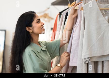 Femme parcourant les vêtements dans le magasin de boutique de mode Banque D'Images