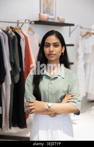 Propriétaire de magasin de mode féminin sérieux debout en toute confiance à l'intérieur Banque D'Images