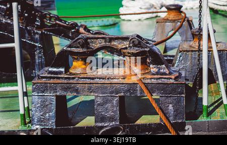 Gros plan de bornes en métal rouillé avec de lourdes cordes sur un pont de navire vert. Banque D'Images