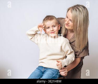 Garçon de 4-5 ans garçon assis sur les genoux de maman maman souriant et regardant le garçon, le garçon montre un doigt vers le bas, à la fois l'apparence européenne blonde de bleu Banque D'Images