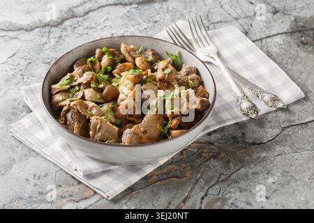 Abats de poulet sautés avec champignons et oignons gros plan dans un bol sur la table. Horizontal Banque D'Images