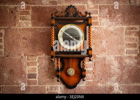 Horloge murale à pendule en bois antique sur le vieux mur de pierre historique Banque D'Images
