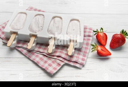 Fraise yogourt popsicles dans un moule sur une serviette à carreaux avec des fraises fraîches Banque D'Images