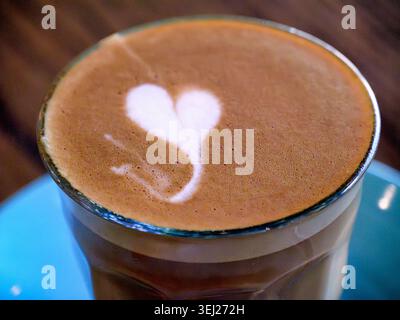 Heart Latte Art Café dans le verre sur plaque bleue Banque D'Images