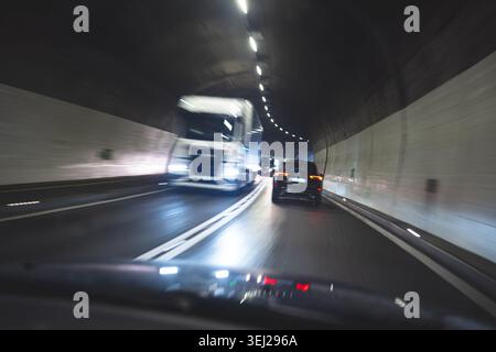 Une vue dynamique orientée vers l'avant de l'intérieur d'un véhicule se déplaçant dans un tunnel éclairé, mettant en évidence le flou de mouvement et la proximité d'un c Banque D'Images