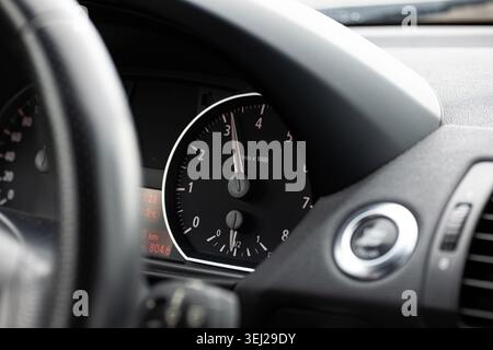 Gros plan détaillé du tableau de bord d'une voiture mettant l'accent sur l'aiguille du tachymètre pointant près de 3000 tr/min alors que le véhicule est en mouvement Banque D'Images