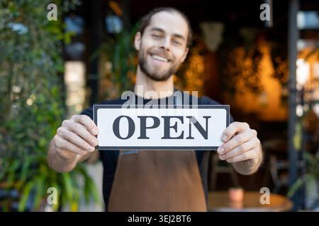 Gros plan du barista souriant montrant un panneau ouvert à la caméra Banque D'Images