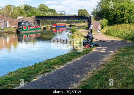 Un pêcheur et des marcheurs sur le chemin de halage du canal Dudley à Old Hill près de Blackheath, West Midlands, Angleterre Royaume-Uni Banque D'Images