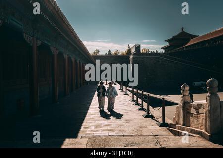 Silhouette de femmes à Hanfu marchant le long de hauts murs de la Cité interdite Pékin, Chine : photo atmosphérique de touristes en robe traditionnelle marchant vers le bas Banque D'Images