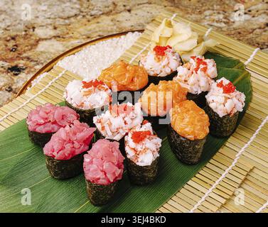 Nourriture, Un plateau de sushis coloré présente différents types de sushis, y compris le thon, le crabe et le saumon. Le sushi est élégamment disposé sur un tapis de bambou Wit Banque D'Images