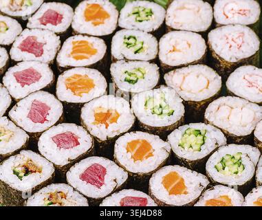 Nourriture, Un assortiment coloré de rouleaux de sushi est disposé sur un plateau, présentant différentes garnitures comme le thon, le saumon, le concombre et le crabe. Ce vibrant Banque D'Images