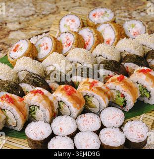 Nourriture, Un assortiment coloré de rouleaux de sushi disposés soigneusement sur un tapis de bambou. Les différents types comprennent les rouleaux californiens, les rouleaux de thon épicés et les rouleaux de tempura Banque D'Images