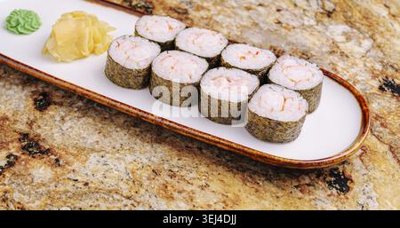 Nourriture, Une assiette de rouleaux de sushi fraîchement préparés est affichée sur un comptoir. Les rouleaux sont soigneusement disposés, accompagnés de wasabi et de gingembre mariné, showc Banque D'Images