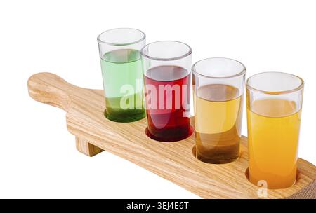 Nourriture, Un plateau en bois peut contenir quatre verres remplis de cocktails vibrants. Les boissons sont vertes, rouges, ambrées et oranges, présentant une variété de saveurs Banque D'Images