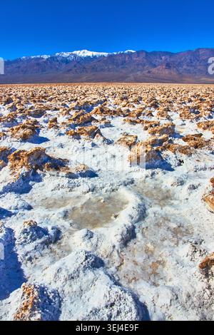 Devil's Golf course, formations salines accidentées et montagnes enneigées dans la Vallée de la mort Banque D'Images