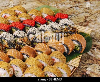 Food, Un plateau de sushis magnifiquement arrangé avec différents types de rouleaux. La scène est animée, parfaite pour un rassemblement festif où les individus Banque D'Images