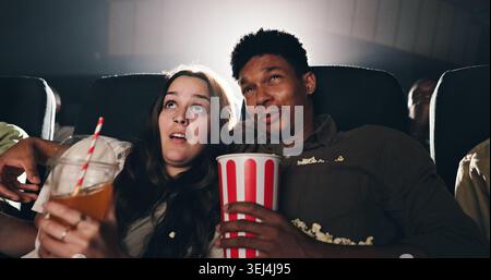 Couple, pop-corn et suspense film au théâtre avec collation, date et divertissement à la projection de film. Les gens, l'homme et la femme avec le choc pour thriller In Banque D'Images