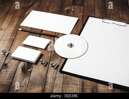 Photo de l'ensemble de papeterie vierge : papier, presse-papiers, en-tête, carte de visite, enveloppe, cd et crayon sur fond de table en bois vintage. ID d'entreprise Banque D'Images