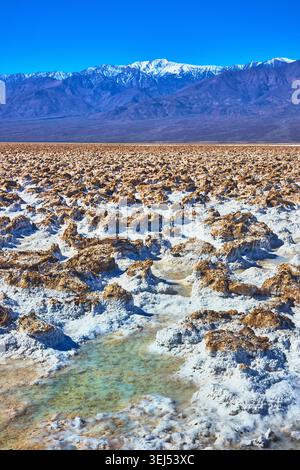 Piscine d'eau des formations salées et montagnes Snowy Panamint dans Devil's Golfcourse Banque D'Images