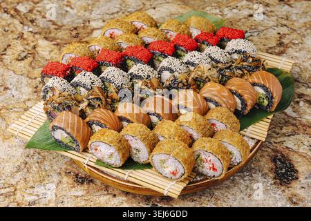 Nourriture, Un plateau coloré dispose d'un assortiment de rouleaux de sushi soigneusement disposés. Les différents types comprennent le saumon, le crabe et nappé de graines de sésame. FR Banque D'Images