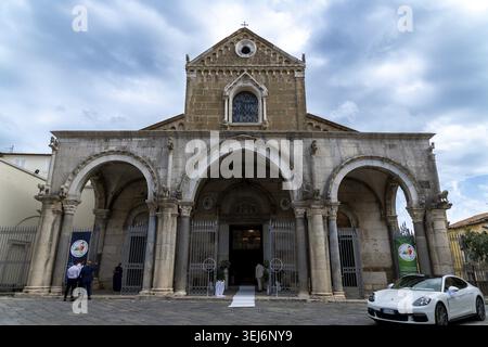 Sessa Aurunca - Campanie - Italie - 08-29-2025 : vue de face de Cattedrale Di Sessa avec portique voûté, invités à l'entrée et une voiture de sport blanche PA Banque D'Images