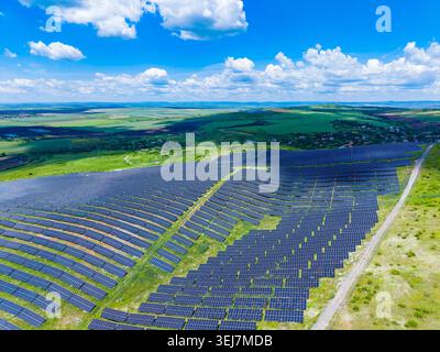 Panneaux solaires à vue aérienne s'étendant sur des terres agricoles sous un ciel bleu vibrant, rangées de modules photovoltaïques formant des motifs géométriques, installation à l'échelle utilitaire Banque D'Images