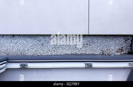 Vue rapprochée d'un détail de construction montrant une couche de gravier sous un mur de béton avec solin métallique et système de drainage visible sur le bord inférieur Banque D'Images