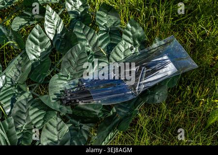 Feuilles de lierre en plastique artificiel placées sur la pelouse, une clôture artificielle à attacher à la clôture, clôture de la parcelle voisine, panneaux de lea en plastique Banque D'Images