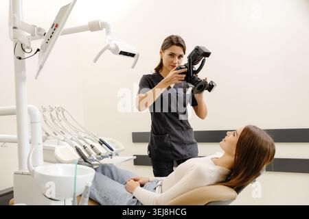 Femme dentiste photographiant avec un appareil photo professionnel le résultat de son travail en clinique. Banque D'Images