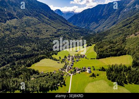 Vue aérienne du village alpin dans la vallée de montagne, Autriche. Prise de vue aérienne époustouflante par drone d'un petit village traditionnel aux champs verdoyants nichés Banque D'Images