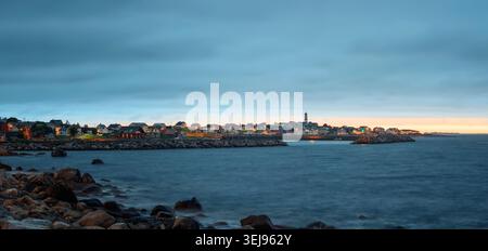 Alnes, Norvège - 26 juin 2024 : panorama crépusculaire serein d'un village côtier avec un phare et des maisons illuminées le long d'un rivage rocheux. Banque D'Images