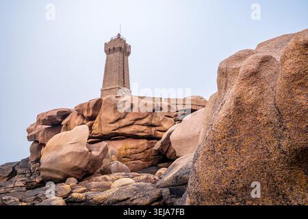 Une perspective à angle bas met en évidence les imposantes falaises et les grands rochers de granit rose à Ploumanac'h. Le phare de pierre de Mean Ruz se dresse sur la somme Banque D'Images
